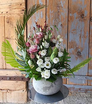 Bouquet de fleurs blanche, rose et verte dans un pot en pierre rond